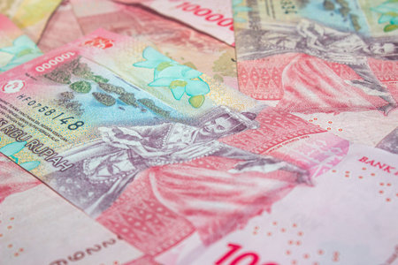 Close-up of Indonesian 100,000 Rupiah banknotes in pink tones.