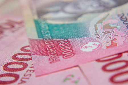 Close-up of Indonesian 100,000 Rupiah banknotes in pink tones.