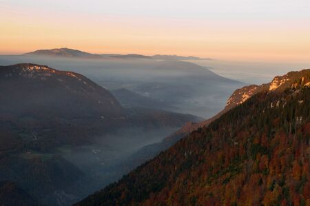 A view into a misty valley on a autumn sunset at the Creux du van in Switzerlandの写真素材