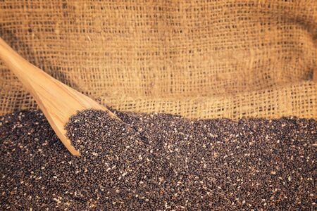 Chia seeds, a healthy source of antioxidants, omega 3 and fiber with wooden spoon on a background of a burlap.の写真素材