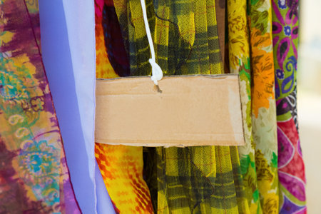 Different Summer ladies scarfs at the market with an empty corrugated cardboard label suitable for...