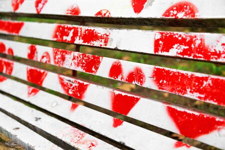 Red hearts painted on a white wooden bench. Love concept.の写真素材