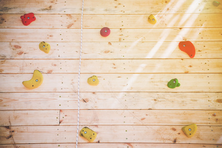 Colorful hand and footholds on a wooden climbing wall in a close up view for a recreational challenge or for practising for the extreme sport of rock climbing  with the sun glow in the right cornerの写真素材