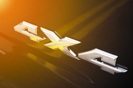 4x4 chrome sign on offroad sport-utility vehicle body with golden glow from the sunの写真素材