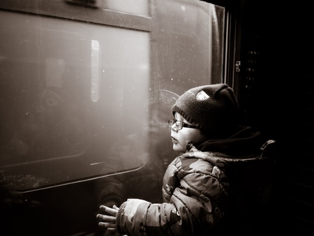 young boy looking out of a train window in black and whiteの写真素材