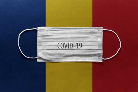 An individual face medical surgical mask on Romania National Flag Background. Health mask. Protection against COVID-19 virus, influenza, SARS. Save Romania from Coronavirusの写真素材