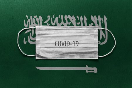 An individual face medical surgical mask on Saudi Arabia National Flag Background. Health mask. Protection against COVID-19 virus, influenza, SARS. Save Saudi Arabia from Coronavirusの写真素材