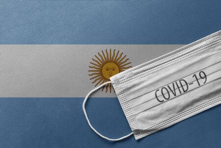 An individual face medical surgical mask on Argentina National Flag Background. Health mask. Protection against COVID-19 virus, influenza, SARS. Save Argentina from Coronavirusの写真素材