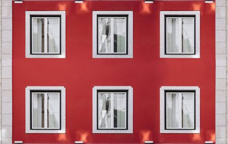 Six vintage windows on a bright red wall. Exterior facade of red historical house with apartments in...