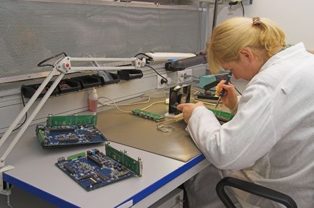 Engineer working with circuits - A woman engineer solders circuits sitting at a table のeditorial素材