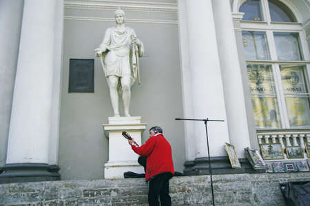 ST PETERSBURG, RUSSIA-MARCH 31, 2008: Street musician playing guitar by sidewalk in front of antique building in Saint Petersburg, Russiaのeditorial素材