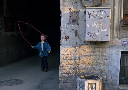 ST PETERSBURG, RUSSIA-APRIL, 2008: Small girl playing jumping rope in poor area in city outskirts in Saint Petersburg, Russiaのeditorial素材