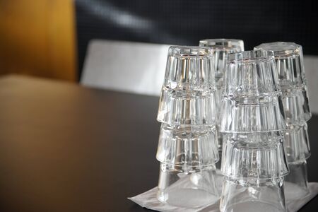Clean drinking glasses stacked on a black table in a cafe.の写真素材