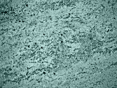 A close-up of a surface of treated greenish granite rock plate. A fragment of a stone wall decoration. Texture of bright granite facing material.の写真素材