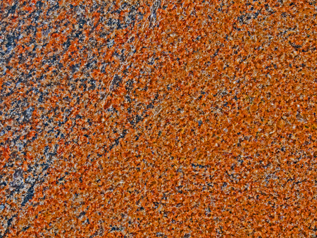 A close-up of a surface of treated brick-colored granite rock plate. A fragment of a stone wall decoration. Texture of brown granite facing material.の写真素材