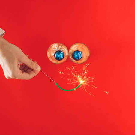 Glasses and blue Christmas decorations  with sparklers on red background.  Minimal Flat lay concept.の写真素材