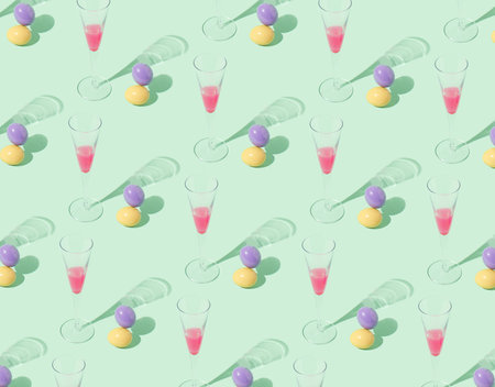 A pattern made of champagne glasses and colorful Easter eggs on a pastel green background. Creative...