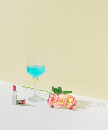 A love concept made of flowers, lipstick and a champagne glass on a pastel beige and white...