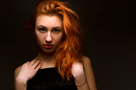 Portrait girl with red hair on a black background closeupの写真素材