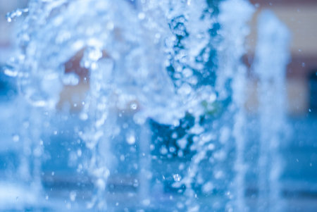 The gush of water of a fountain. Splash of water in the fountain, abstract image. bokeh of blue...