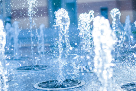 The gush of water of a fountain. Splash of water in the fountain, abstract image. bokeh of blue...