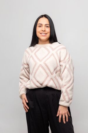 Portrait of a smiling Young beautiful lovely brunette girl in a warm winter sweater on light gray background.の写真素材