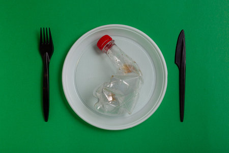 Plastic disposable utensils on green background. fork, knives, plates