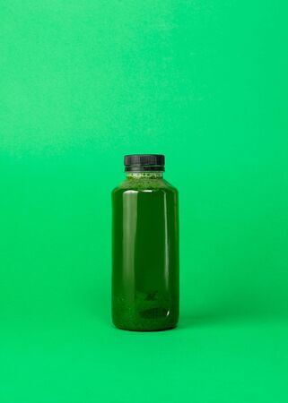 Fresh celery spinach juice in a plastic bottle isolated on green background. Healthy eating Detox juice dietの写真素材