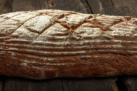 Fresh baked bread at brown wooden table. brown coarse grain bread