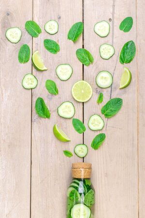 Water bottle with lime and mint on wooden table. Infused water with lemon, cucumber and mint on wooden background. summer drink. Art of fresh fruits. Original supply of summer fresh cocktail.の写真素材