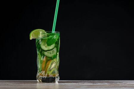 Citrus fruit and herbs infused sassi water for detox or dieting in glass bottles on wooden board, dark background, selective focus, square crop. Clean eating, weight loss, healthy lifestyle conceptの写真素材