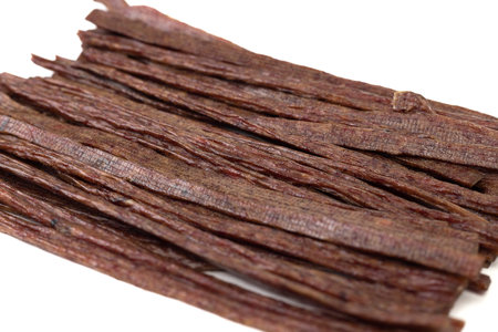 Dried beef meat sliced on stick, beer snack isolated on white background