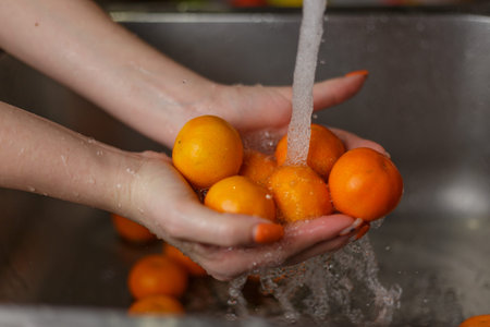 Happy woman washing fruit at kitchen. bananas, tangerines, applesの写真素材
