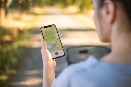 girl cyclist looks at a map on her phone and plots a route for a trip for a GPS navigator. high...