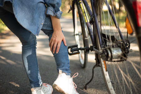 leg pain, cramp after cycling girl in jeans. High quality photo
