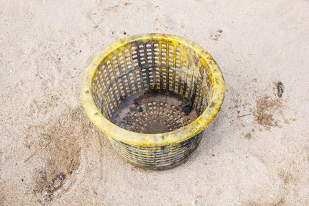 yellow trash basket on sand