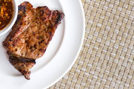 grilled pork on white plate with dip sauceの写真素材