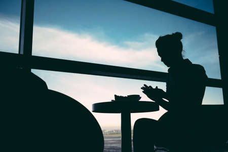 Woman waiting at airport lounge against windowの写真素材