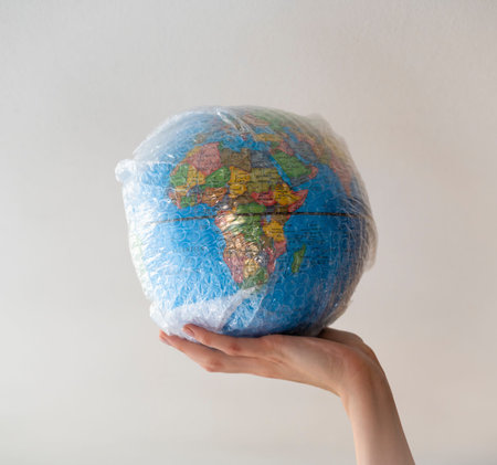 Hand holds a globe wrapped in plasticの写真素材