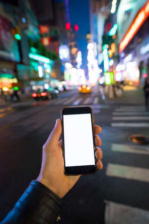 hand holding a mobile phone at night in the cityの写真素材