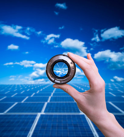 Hand holds optical lens on solar panels