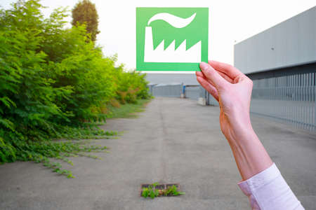 Hand holds green industry symbol against factoryの写真素材