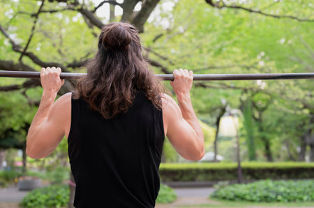 Man exercising on pull-up bar in outdoor park setting