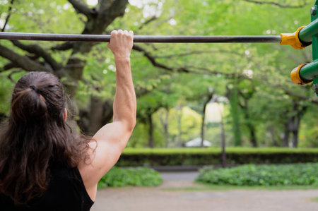 Man exercising on pull-up bar in outdoor park setting