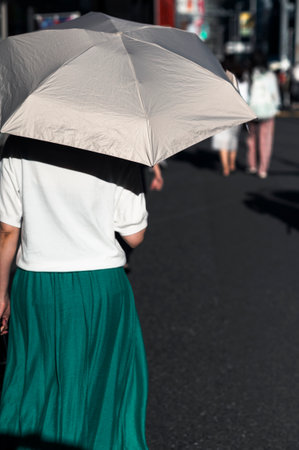 Woman walking under parasol in summer city streetの写真素材