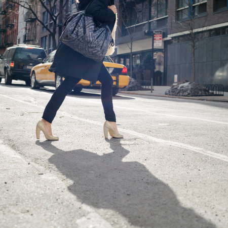 Stylish woman crossing urban street in high heels in NYCの写真素材