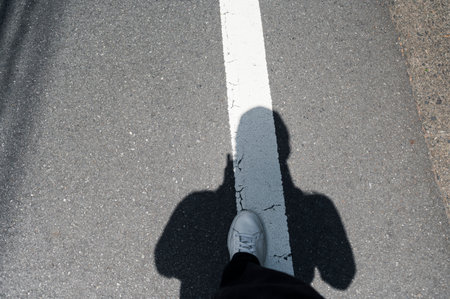 Shadow of person standing over white road lineの写真素材