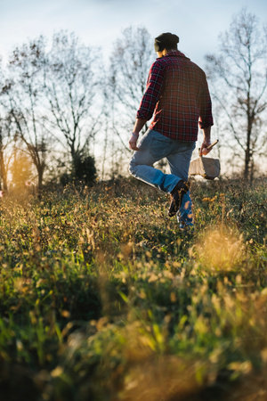 Lumberjack walking through field with axe and firewoodの写真素材