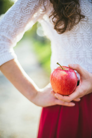 Girl in red skirt holding apple outdoors
