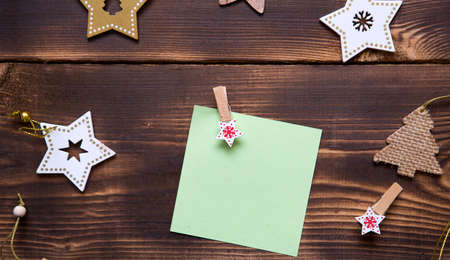 Christmas flat lay of wooden stars, fir trees and clothespins on a dark background with a square sheet for notes in the center. New year's frame, space for text. Xmas toys, to do list, a postcardの写真素材
